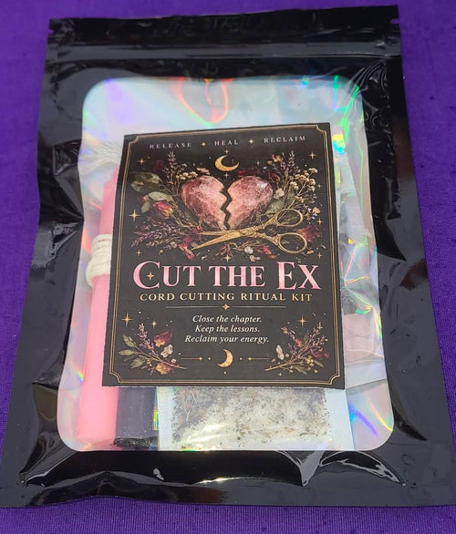 A packaged 'Cut the Ex' cord cutting ritual kit inside a black resealable pouch with an iridescent insert. The front card features a dark background with a broken heart, flowers, and the text 'Release • Heal • Reclaim' and 'Cut the Ex Cord Cutting Ritual Kit'.