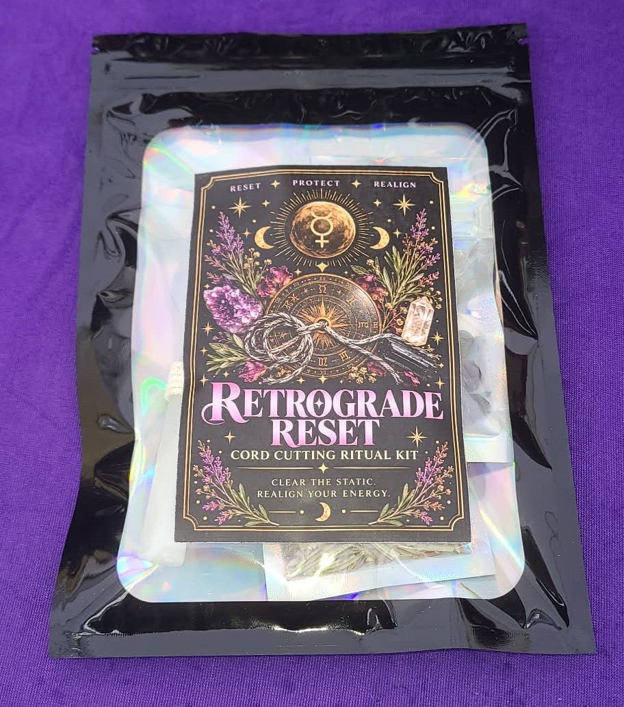 A black holographic pouch containing a 'Retrograde Reset Cord Cutting Ritual Kit' with an illustrated black label, placed on a purple background.
